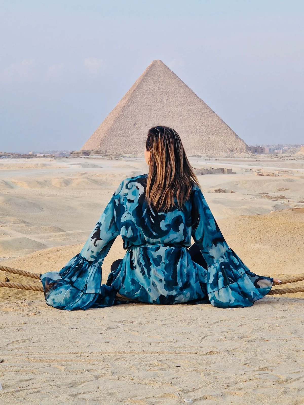 Loukia Papa seated before the Great Pyramid of Giza, watching